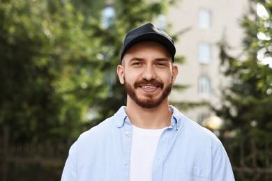 Photo of Portrait of smiling man in baseball cap outdoors