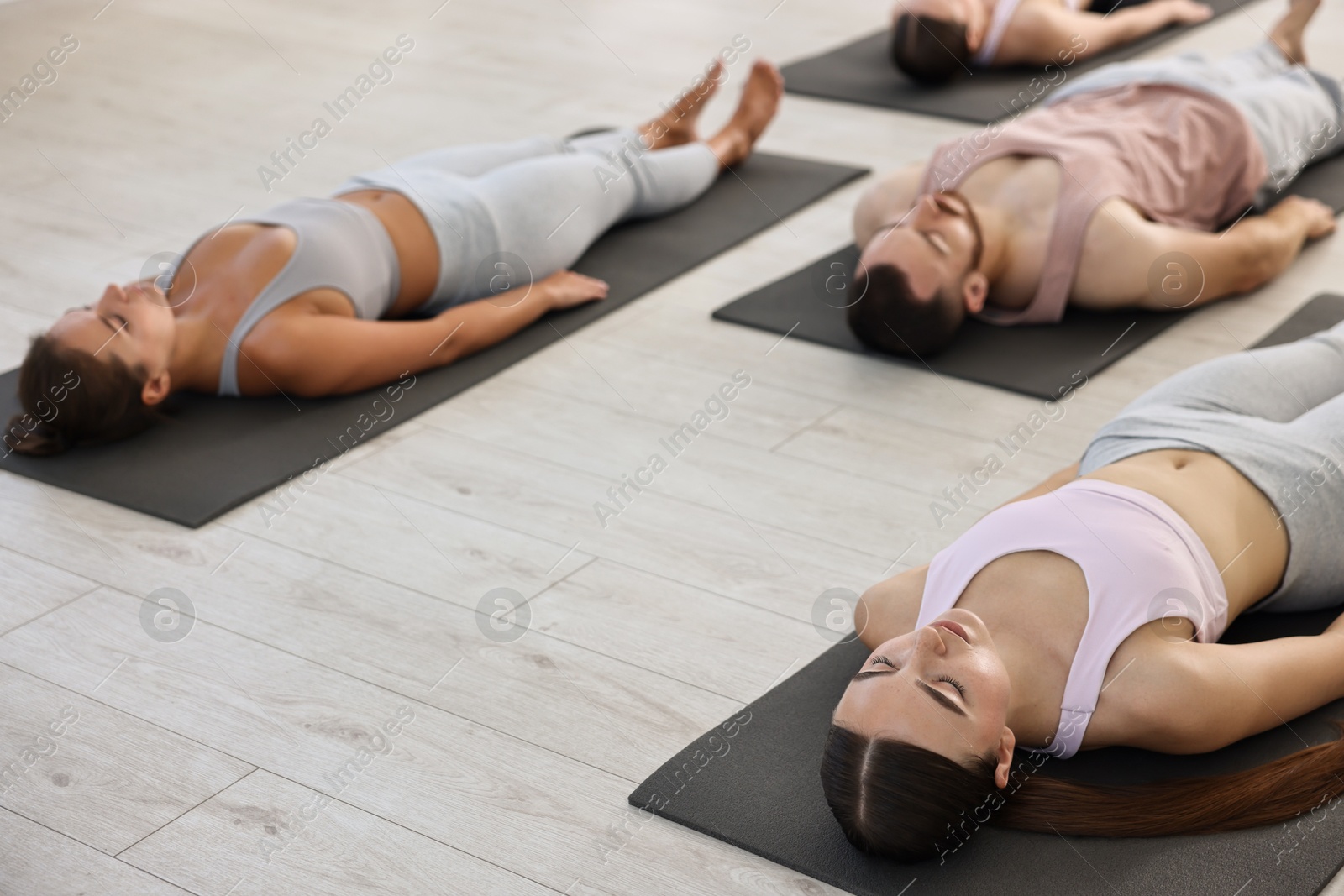 Photo of Group of people meditating on mats in yoga class