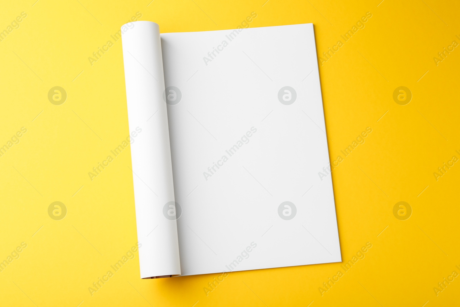 Photo of Open magazine with blank page on yellow background, top view. Mockup for design