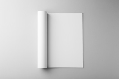 Open magazine with blank page on grey background, top view. Mockup for design