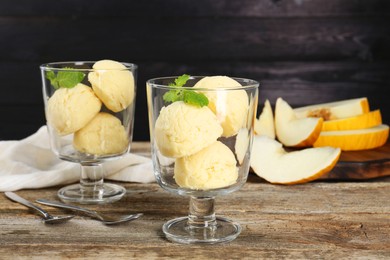 Photo of Scoops of melon sorbet in glass dessert bowls and spoons on wooden table