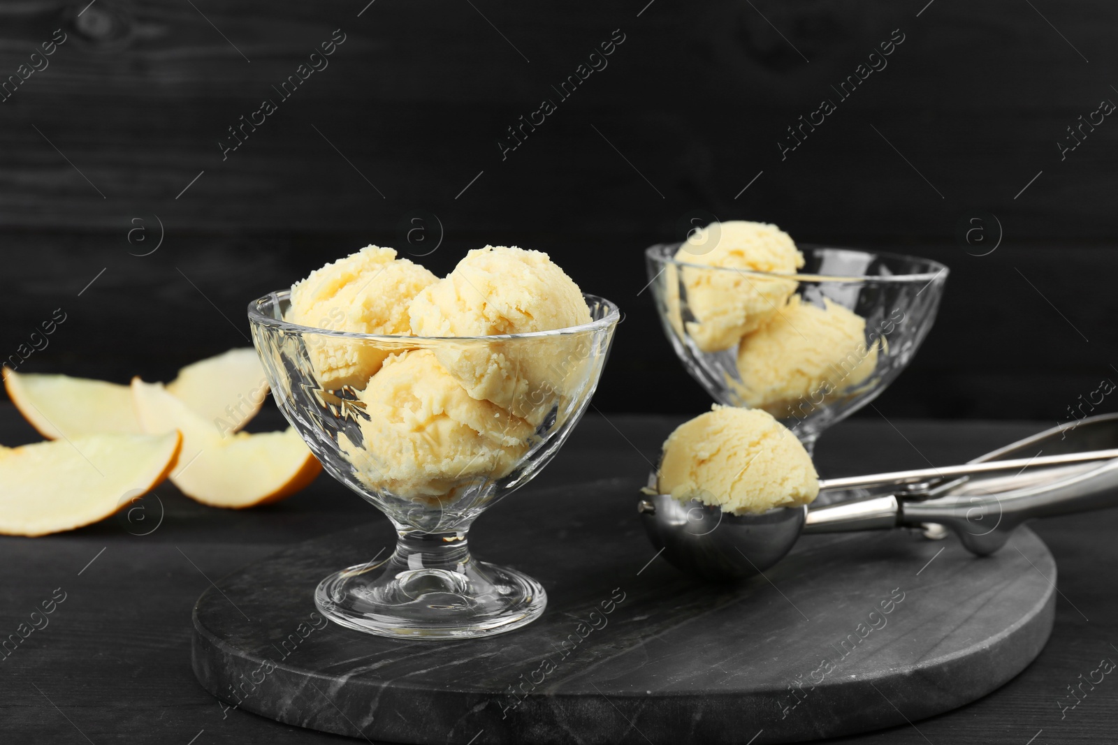 Photo of Scoops of melon sorbet in glass dessert bowls on dark wooden table