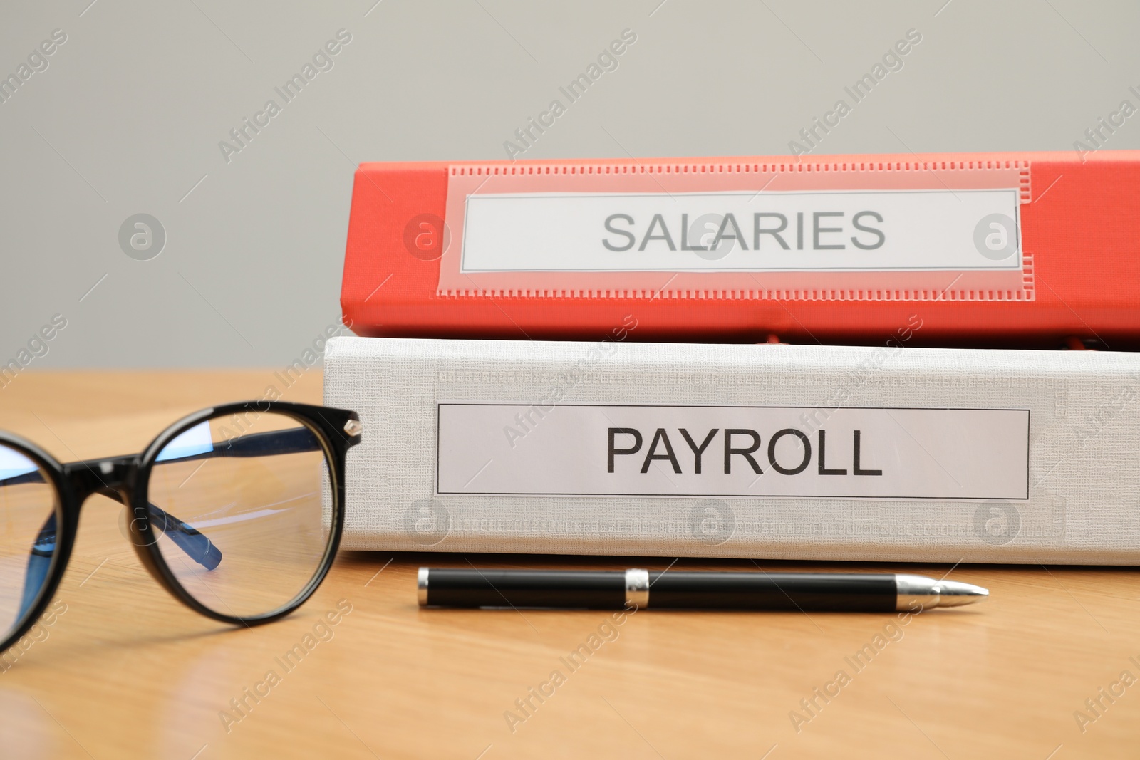 Photo of Payroll. Folders, glasses and pen on wooden table, closeup