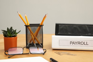 Photo of Payroll. Folders, glasses, houseplant and stationery on wooden table, closeup