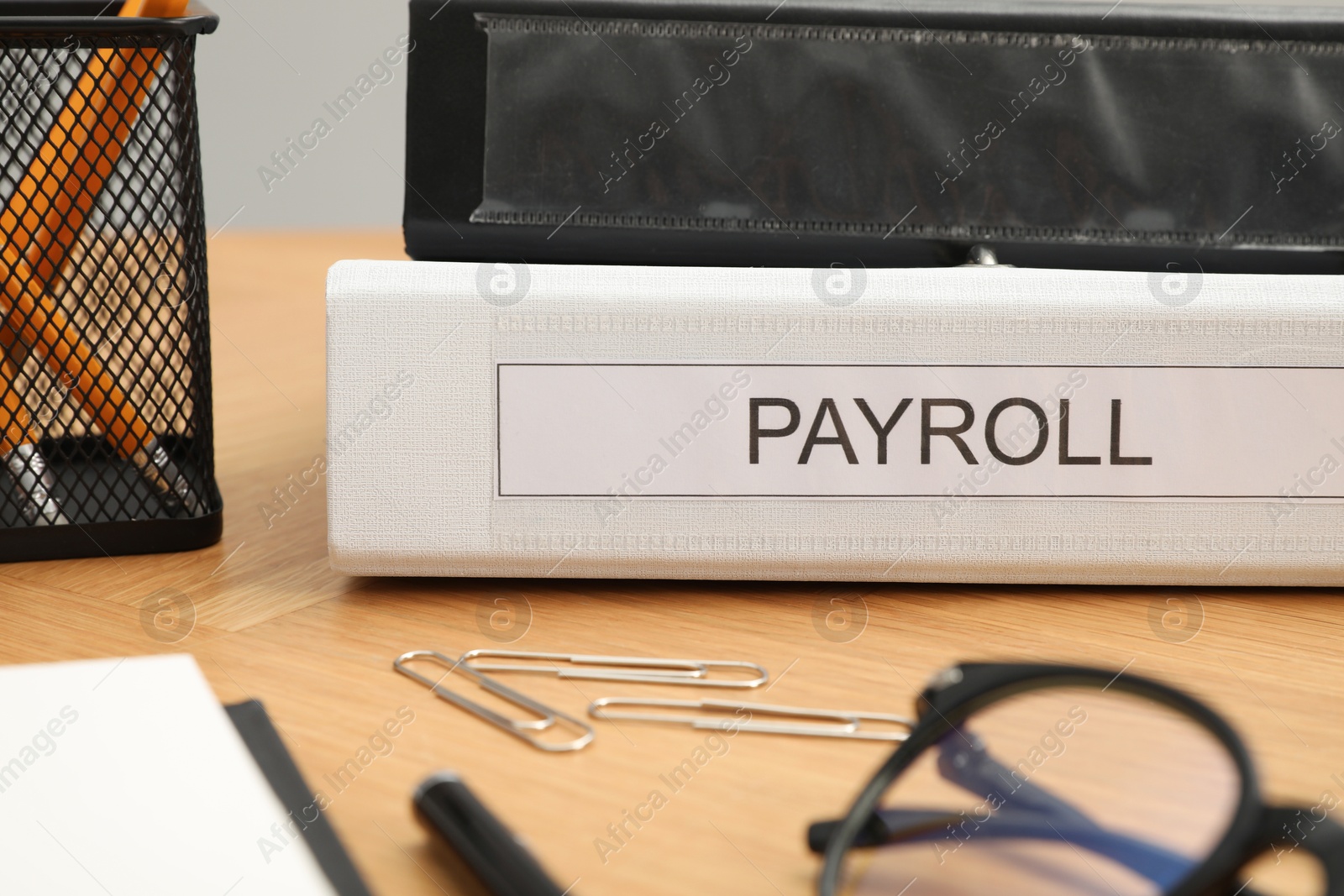 Photo of Payroll. Folders, glasses and paperclips on wooden table, closeup