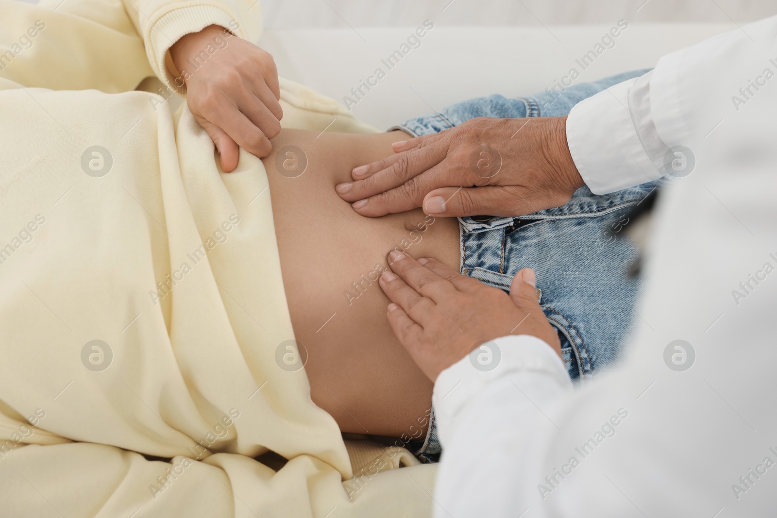 Photo of Doctor examining woman with stomach pain in clinic, closeup