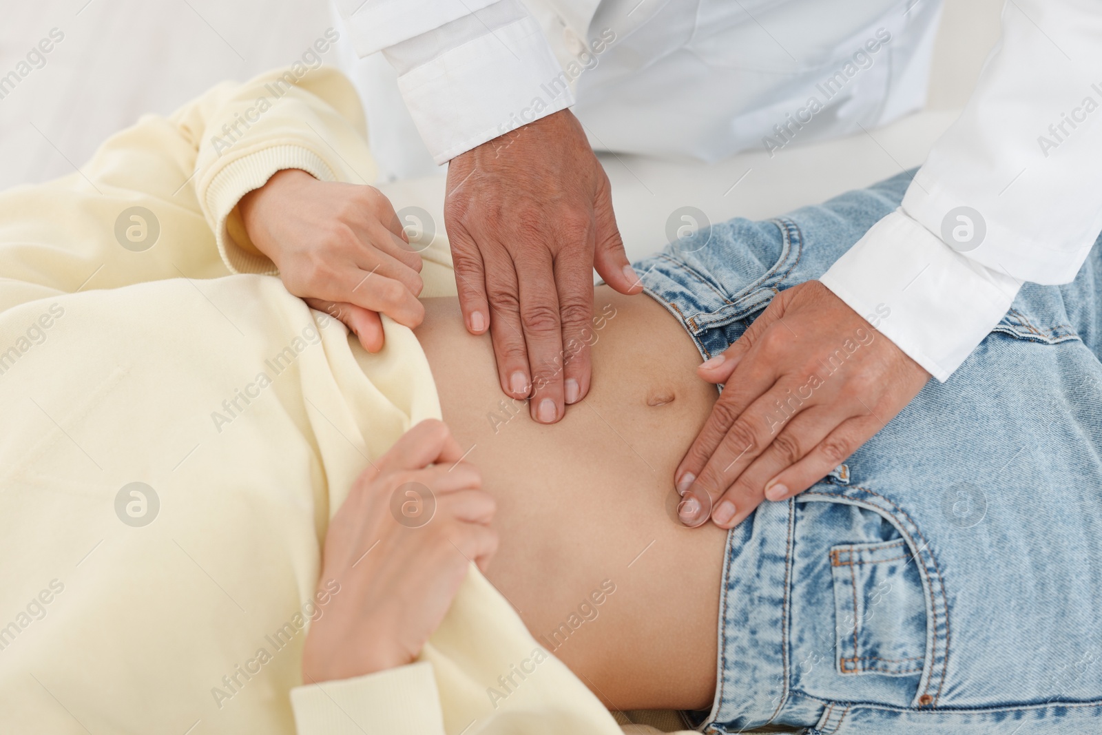 Photo of Doctor examining woman with stomach pain in clinic, closeup