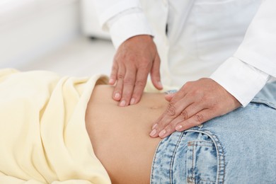 Photo of Doctor examining woman with stomach pain in clinic, closeup