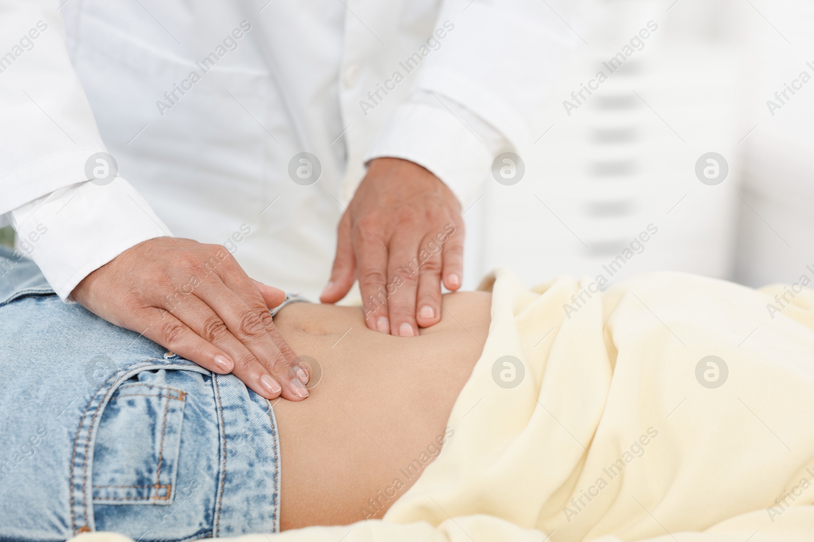 Photo of Doctor examining woman with stomach pain in clinic, closeup