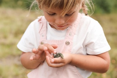 Little girl holding lizard on blurred background. Child enjoying beautiful nature