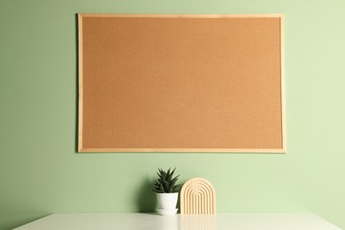 Photo of Cork board and decorative elements on light table near green wall indoors