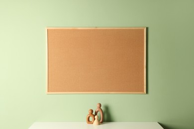 Cork board and decorative figures on light table near green wall indoors