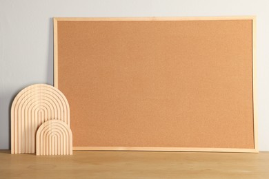 Photo of Cork board and decorative elements on wooden table near light wall