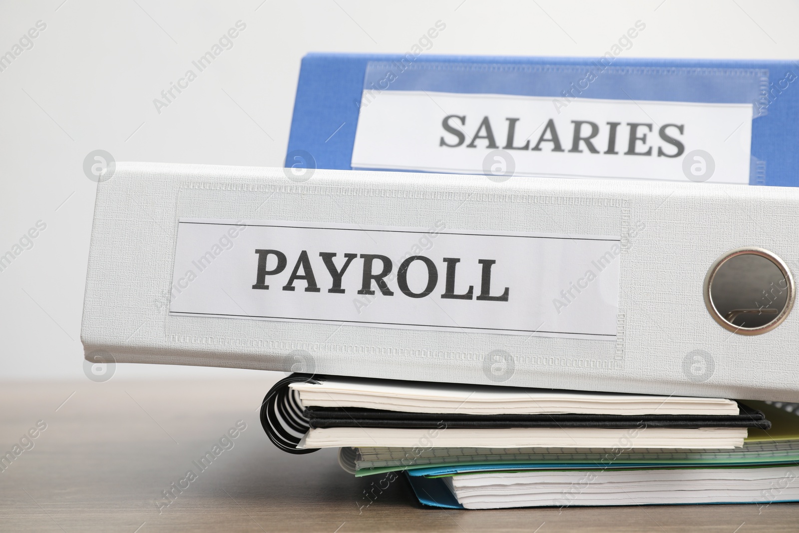 Photo of Office folders with words Payroll and Salaries on wooden table, closeup