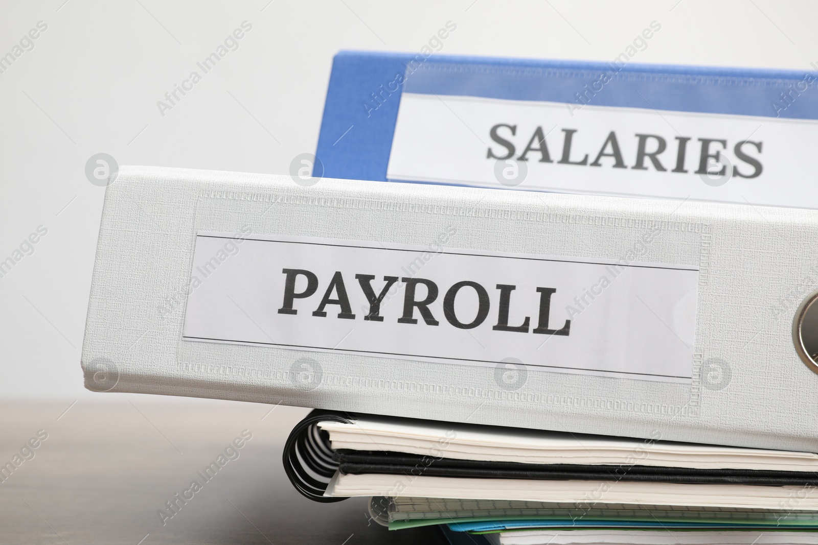 Photo of Office folders with words Payroll and Salaries on wooden table, closeup