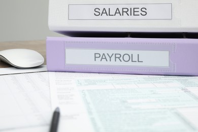 Photo of Payroll. Papers, pen and computer mouse on table, closeup