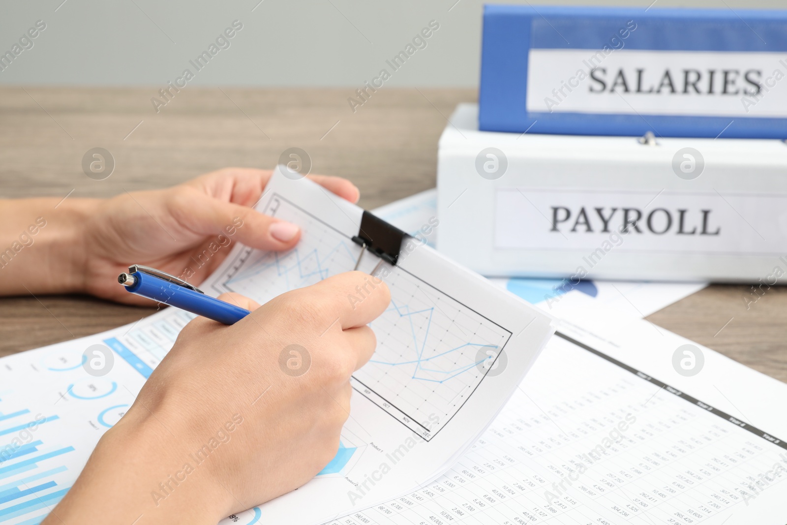 Photo of Payroll. Woman with papers at wooden table, closeup