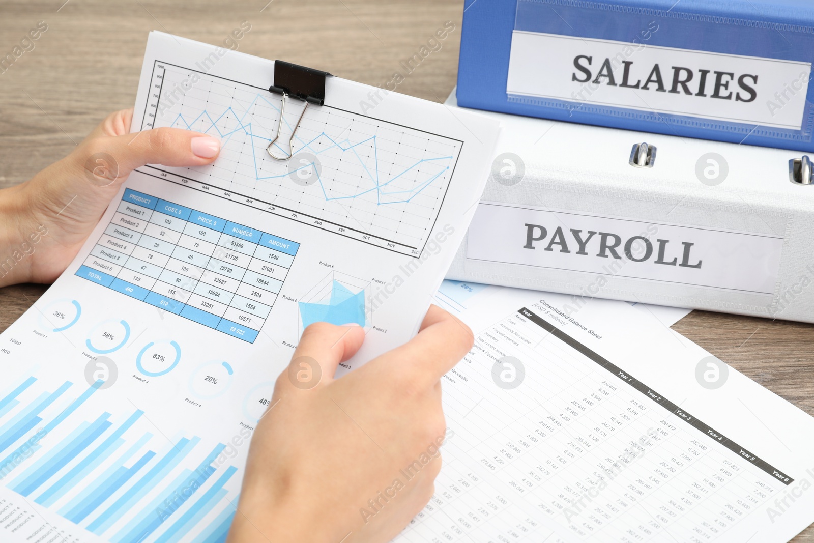 Photo of Payroll. Woman with papers at wooden table, closeup