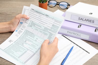 Photo of Payroll. Woman with papers at wooden table, closeup