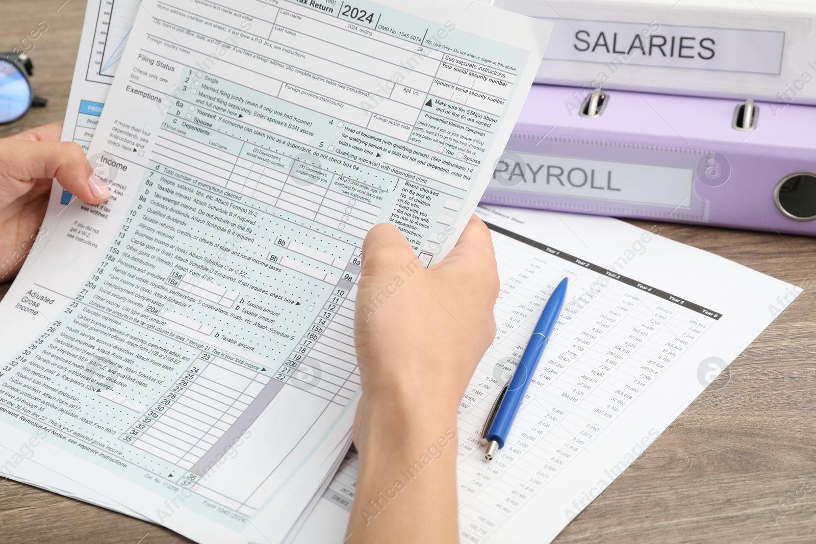 Photo of Payroll. Woman with papers at wooden table, closeup