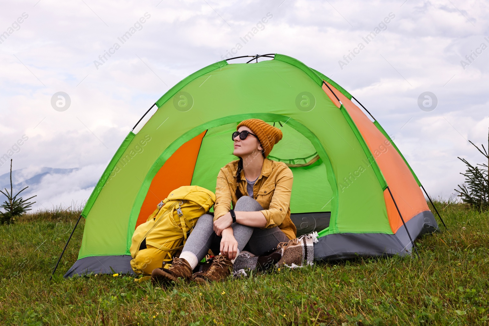 Photo of Young camper and tent in mountains. Active tourism