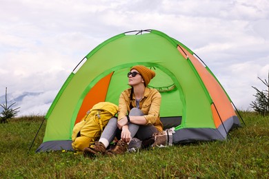 Young camper and tent in mountains. Active tourism