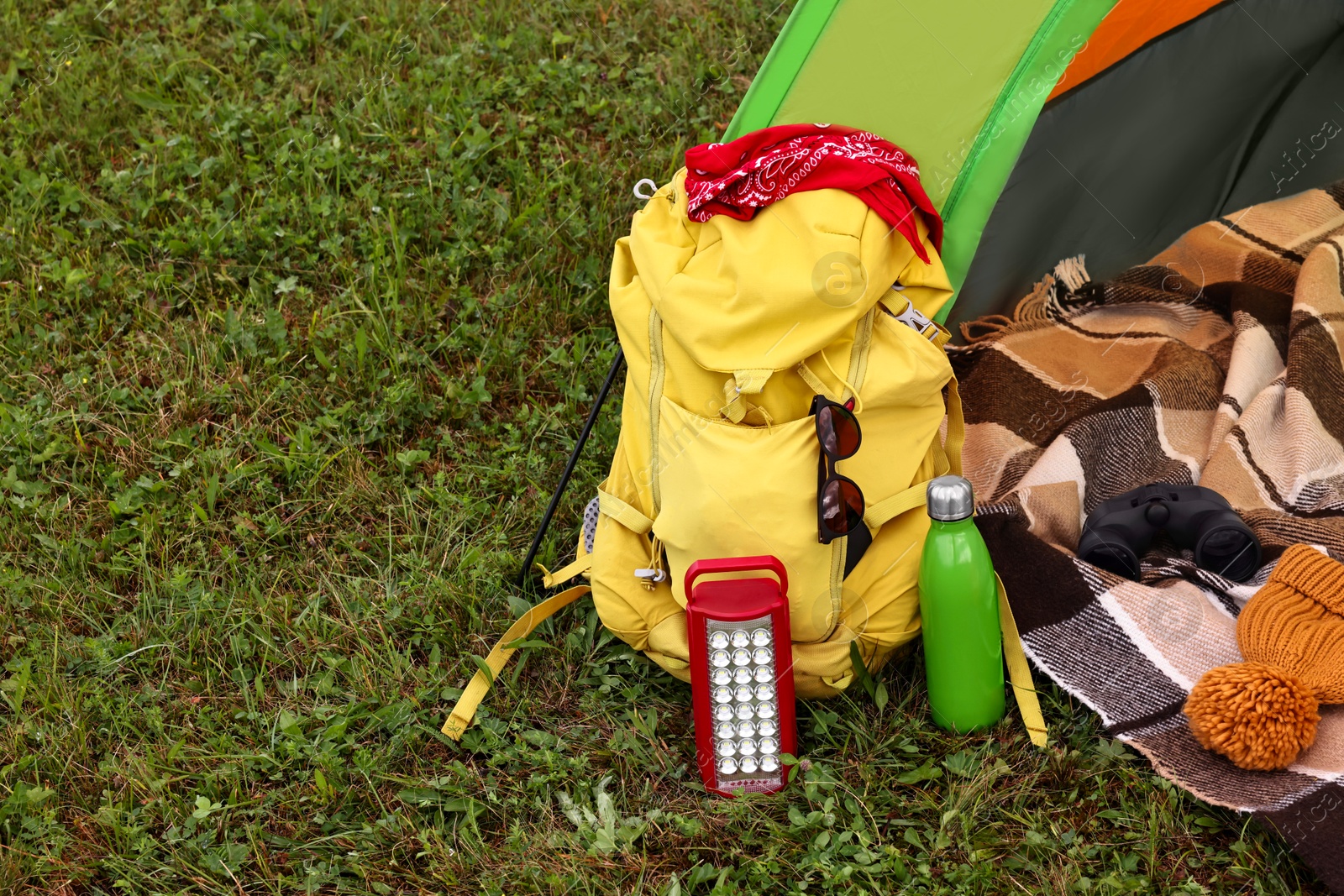 Photo of Tent, backpack and camping equipment on green grass in mountains, space for text