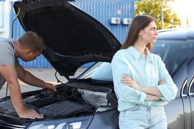 Photo of Man and woman near broken car outdoors