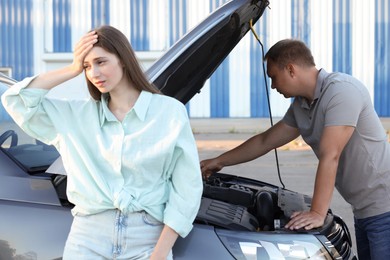 Photo of Man and woman near broken car outdoors