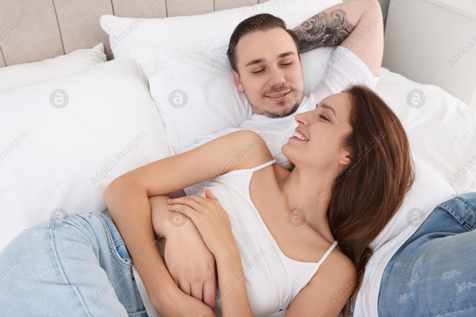 Photo of Happy couple spending time together on bed at home