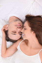 Happy couple spending time together on bed at home, top view