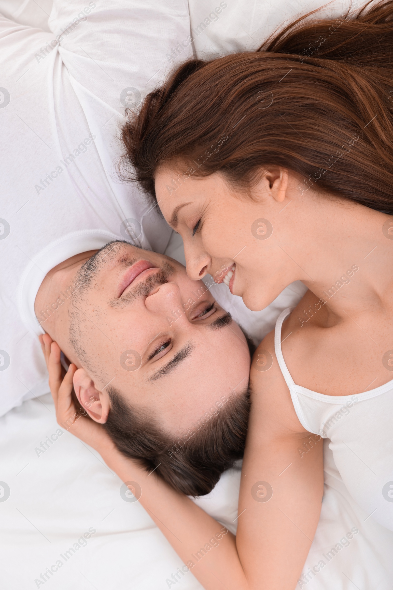 Photo of Happy couple spending time together on bed at home, top view