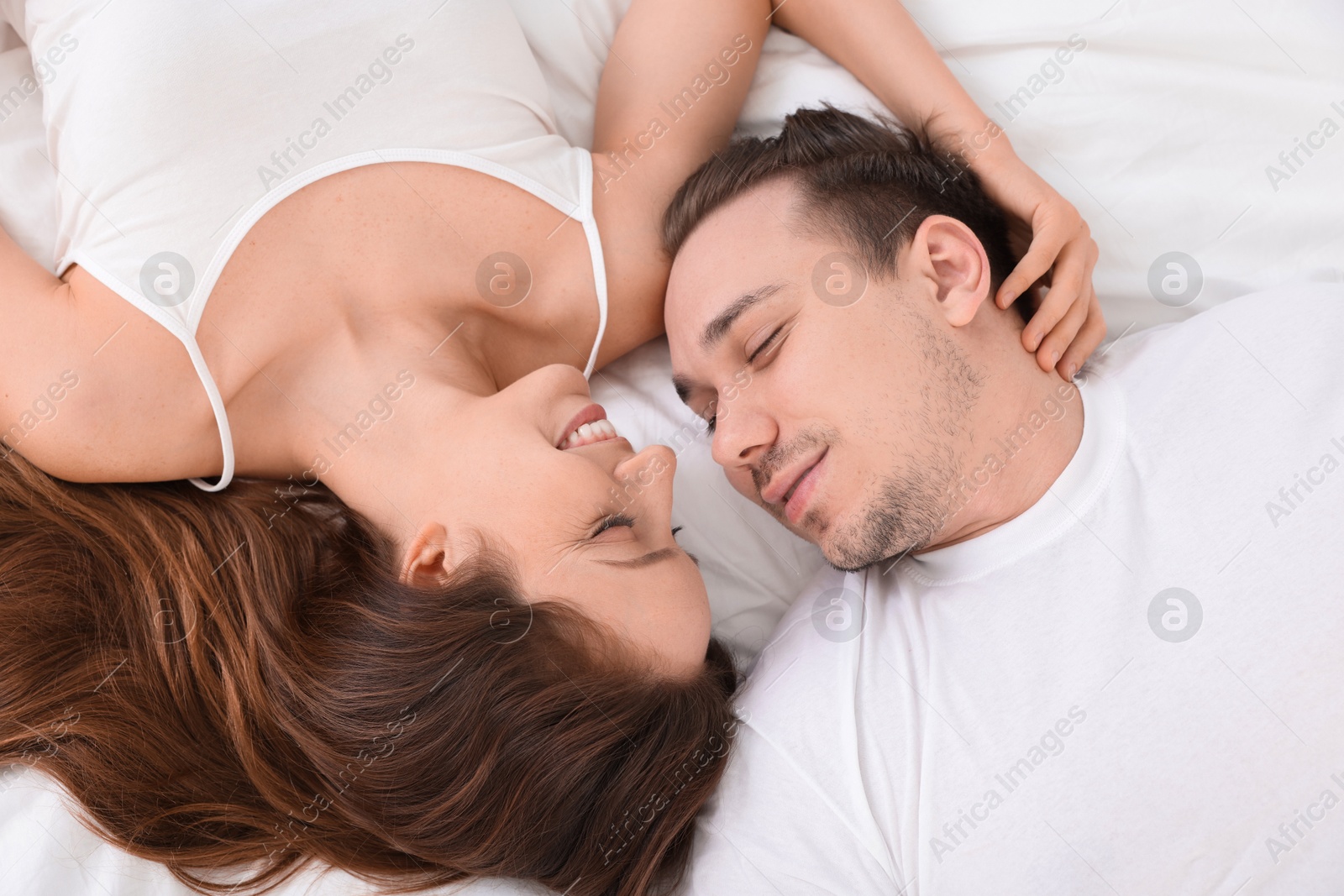 Photo of Happy couple spending time together on bed at home, top view