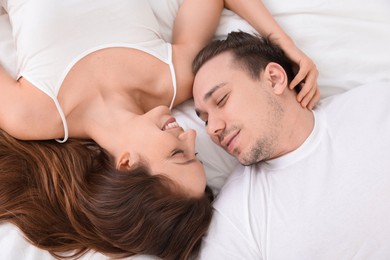 Photo of Happy couple spending time together on bed at home, top view