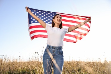 Happy woman with flag of USA outdoors, low angle view