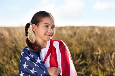 Photo of Little girl with flag of USA outdoors. Space for text