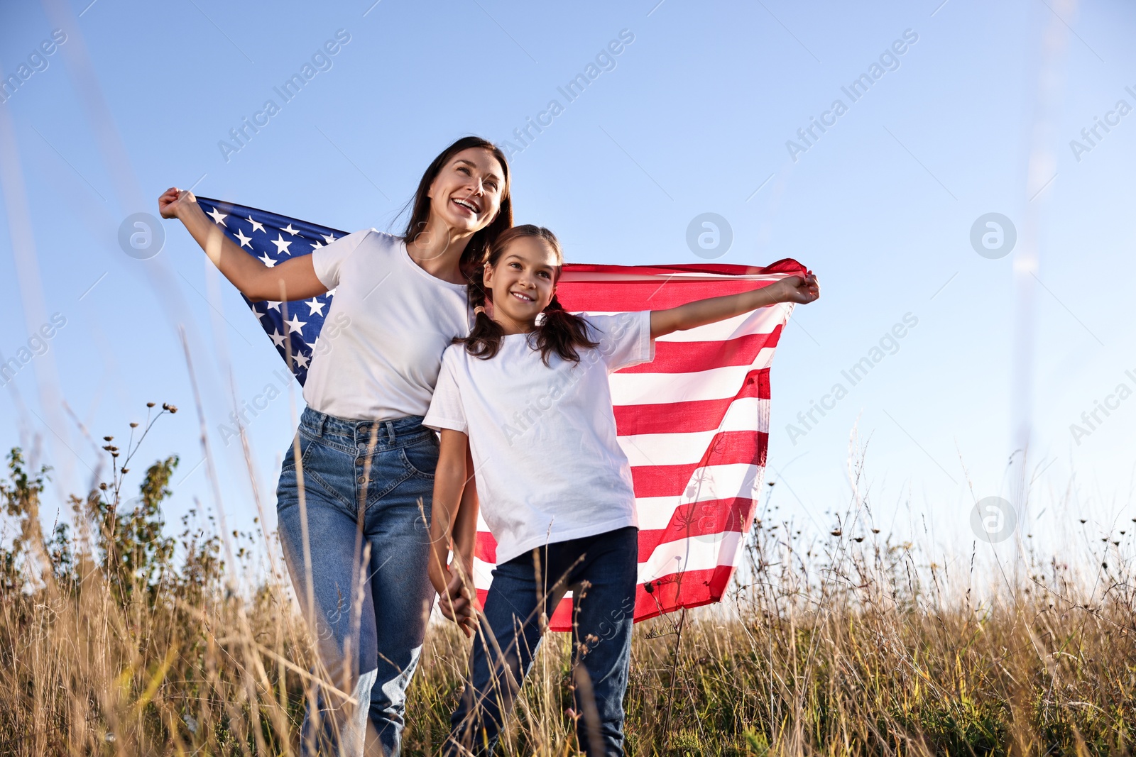 Photo of Happy mother and daughter with flag of USA outdoors, low angle view