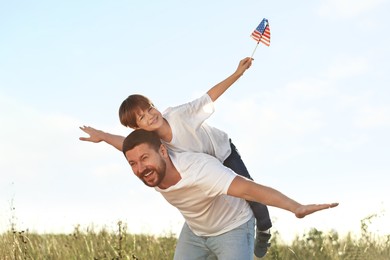 Photo of Happy father and son with flag of USA having fun outdoors