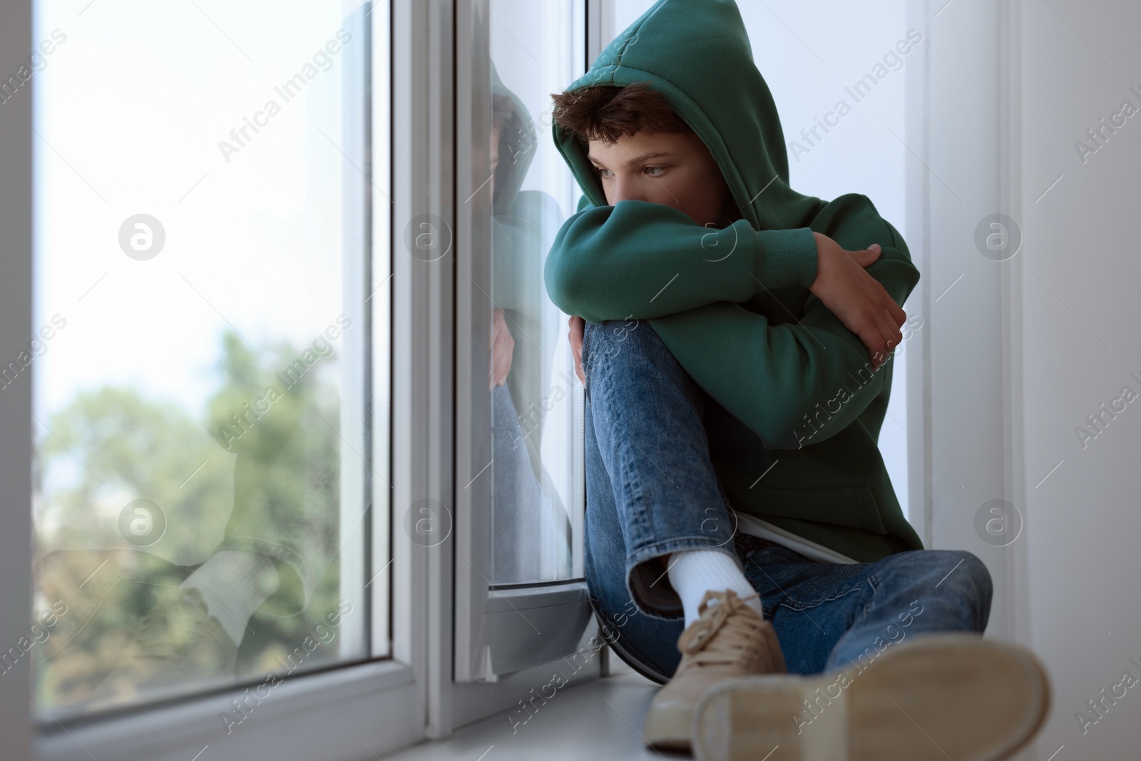 Photo of Loneliness concept. Sad teenage boy on windowsill indoors