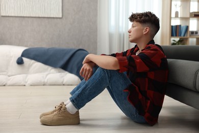 Loneliness concept. Sad teenage boy on floor in bedroom