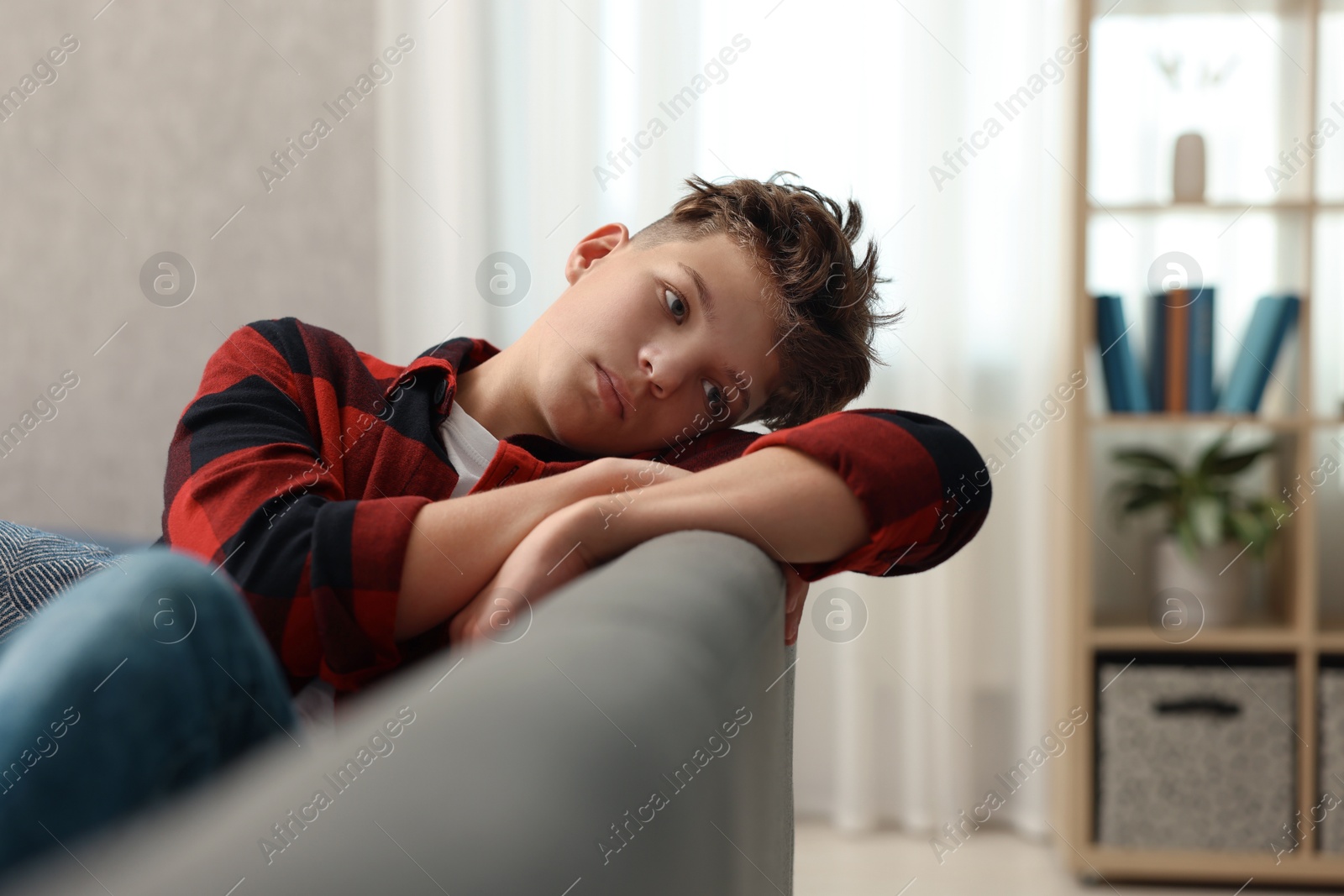 Photo of Loneliness concept. Sad teenage boy on sofa in room