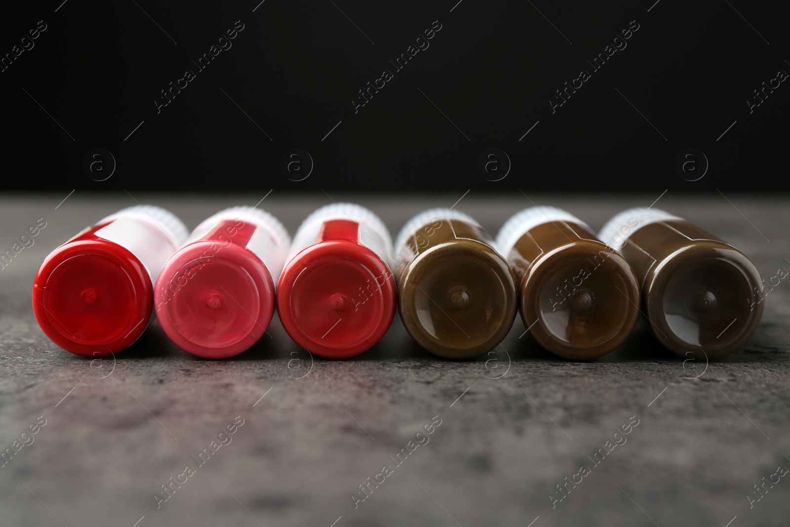 Photo of Bottles of pigments for permanent makeup on grey table, closeup