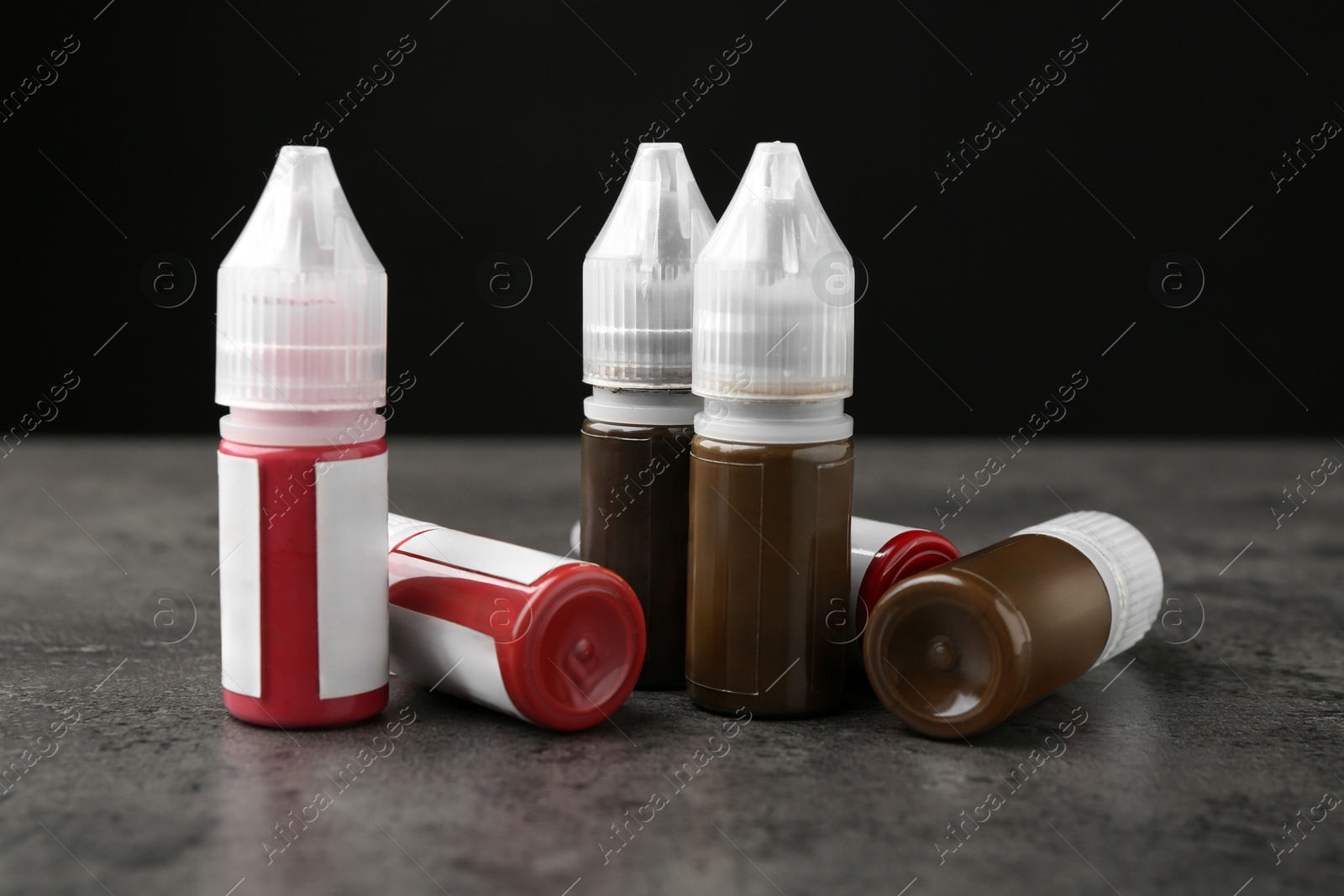 Photo of Bottles of pigments for permanent makeup on grey table