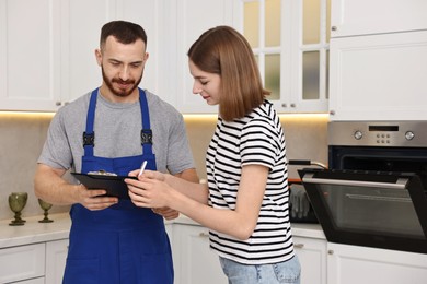 Photo of Woman and repairman signing documents near oven in kitchen