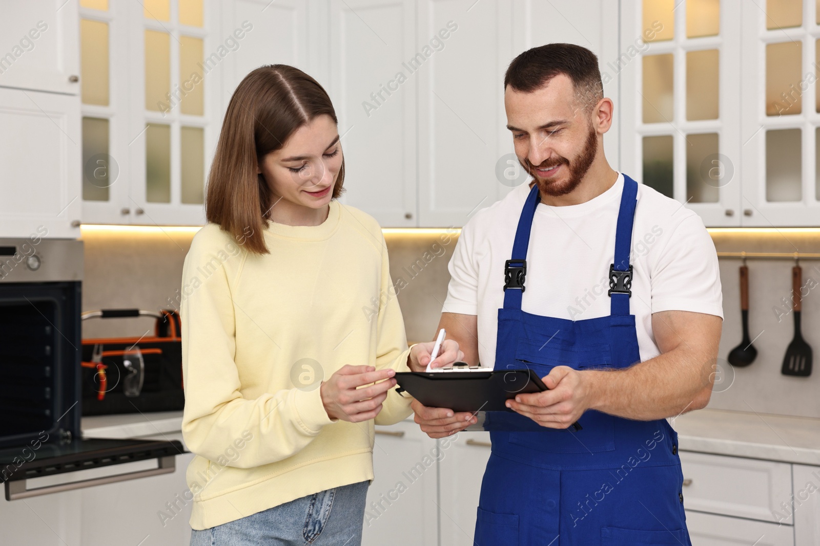 Photo of Woman and repairman signing documents near oven in kitchen