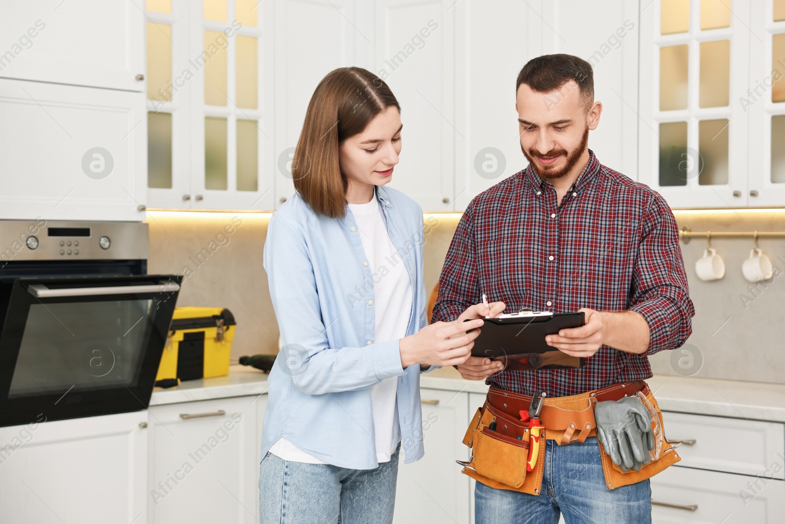 Photo of Woman and repairman signing documents near oven in kitchen