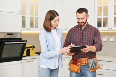 Woman and repairman signing documents near oven in kitchen