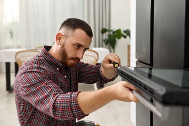 Photo of Repairman with screwdriver fixing oven at home