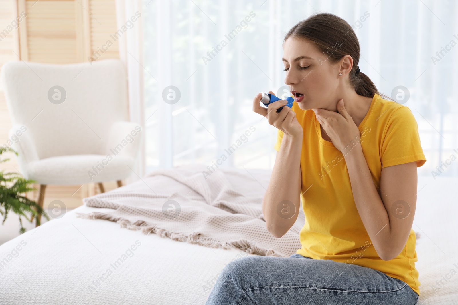 Photo of Young woman using asthma inhaler at home. Space for text