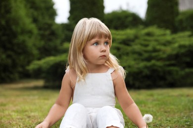 Cute little girl on green grass outdoors. Child enjoying beautiful nature